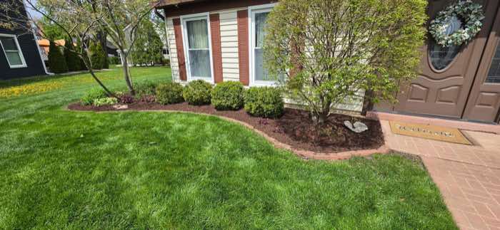 The same front bed with fresh mulch, a cut edge, and a freshly mown lawn