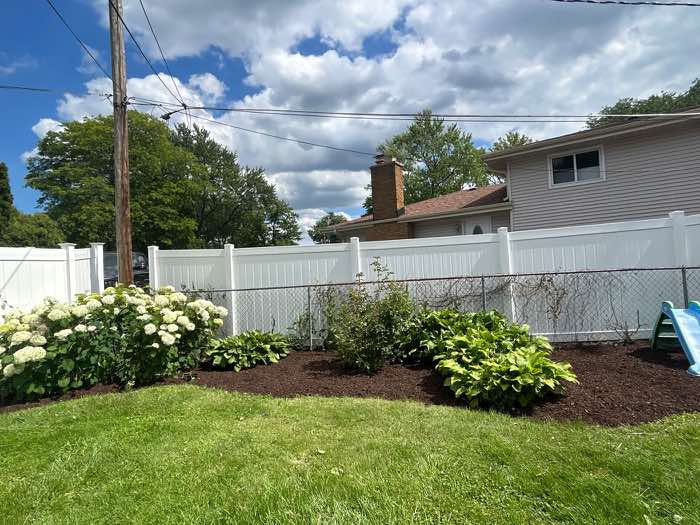 Mulched beds along a white fence